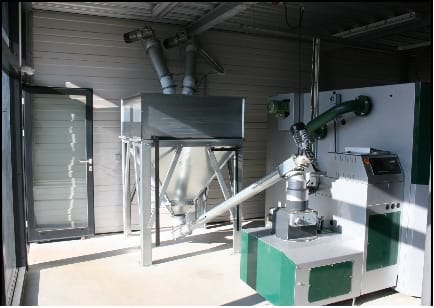 Una sala industrial con equipos de transporte de pellets por medio de un sinfín.